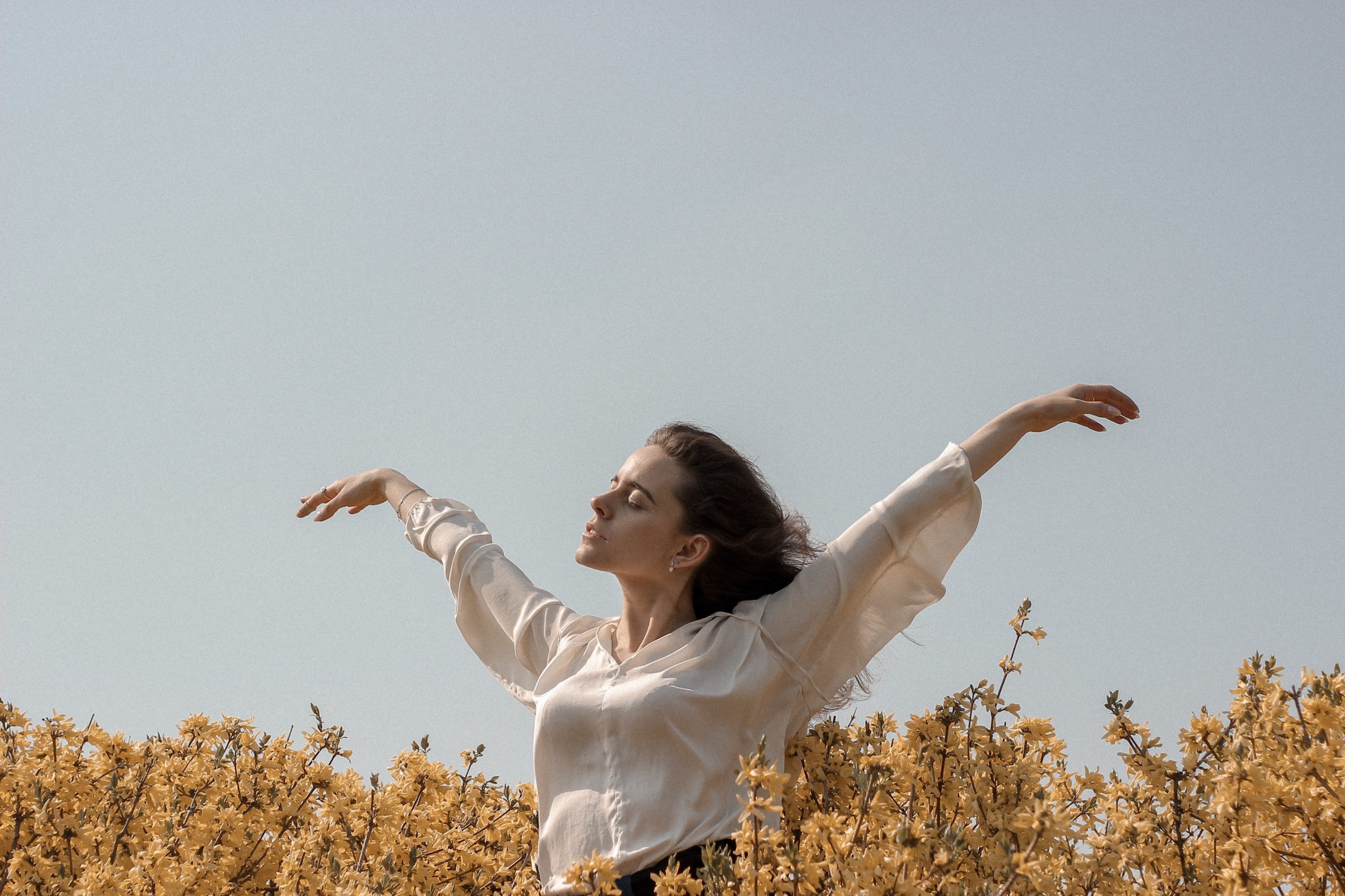 Woman reaching her arms out feeling at peace in the middle of a field showing her self-esteem