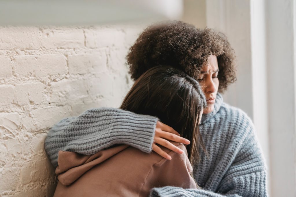 Sad women hugging at home due to feeling out of control due to low self-esteem