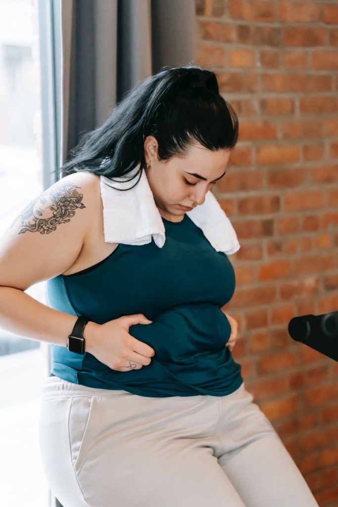 Woman has just done a workout to help her feel better about herself, but she still doesn't show herself compassion and is being negative about her body.