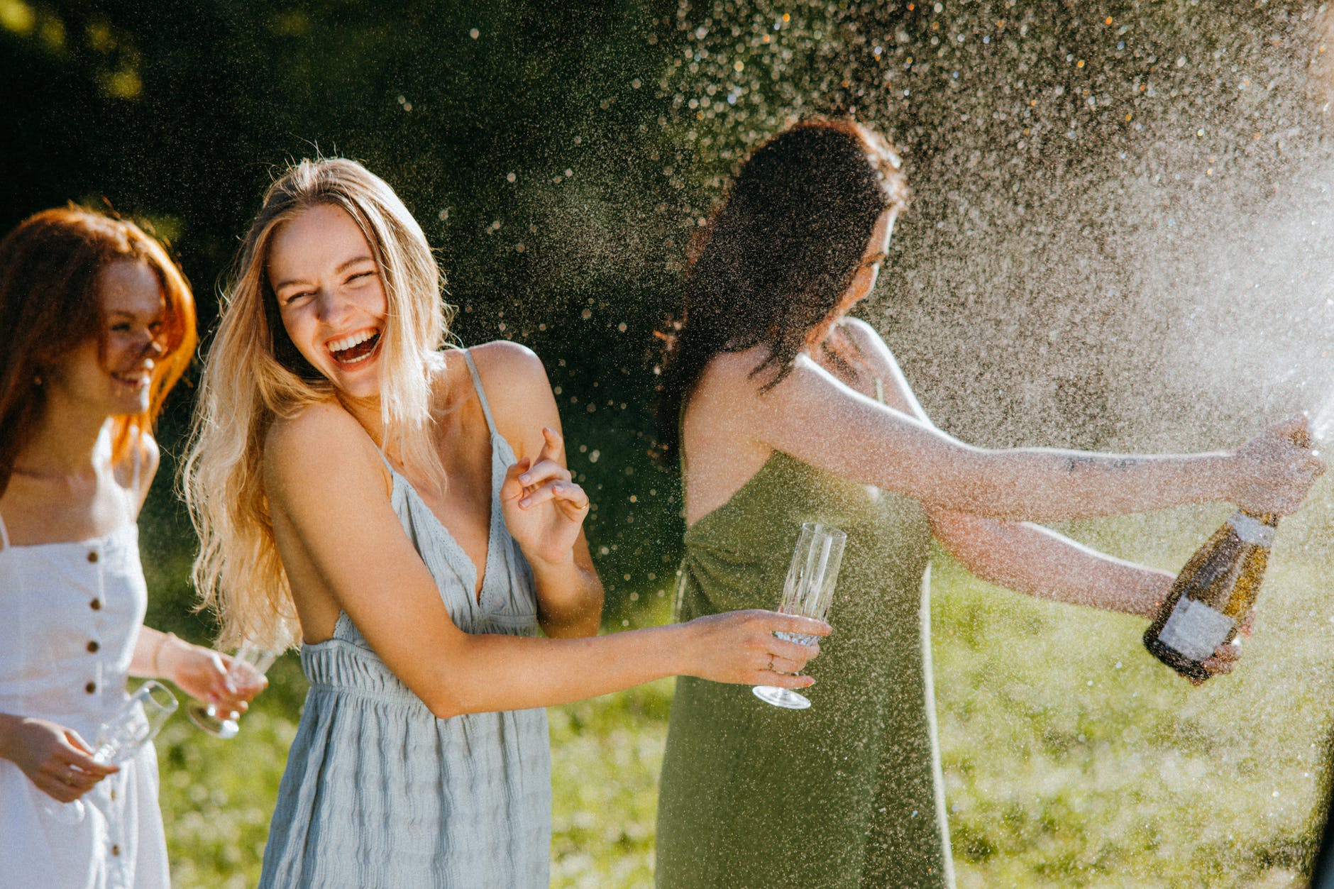 women having fun while splashing liquid from the bottle