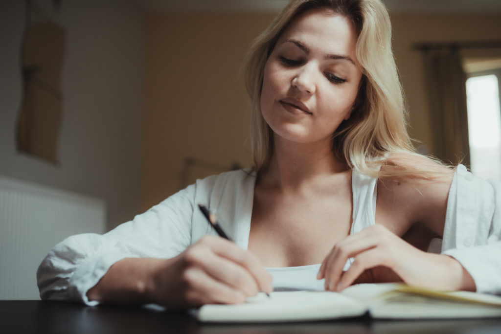 Woman writing in a notebook to help build body acceptance