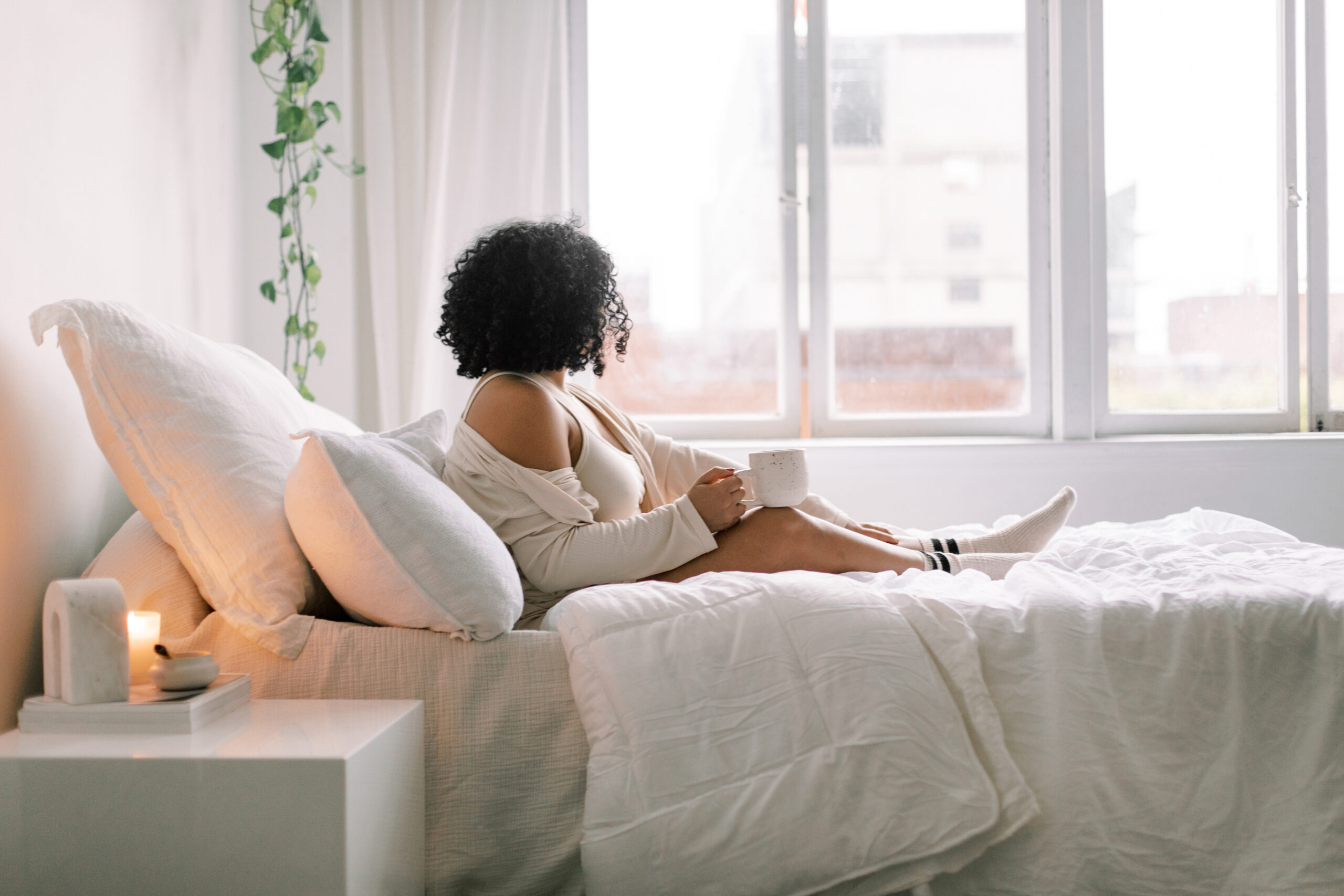 How to handle bad body image days. Woman sat on bed looking out a window.