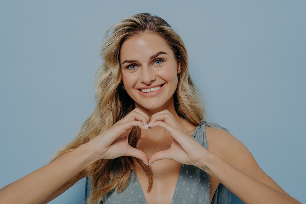 Woman showcasing gratitude by making a heart with her hands.