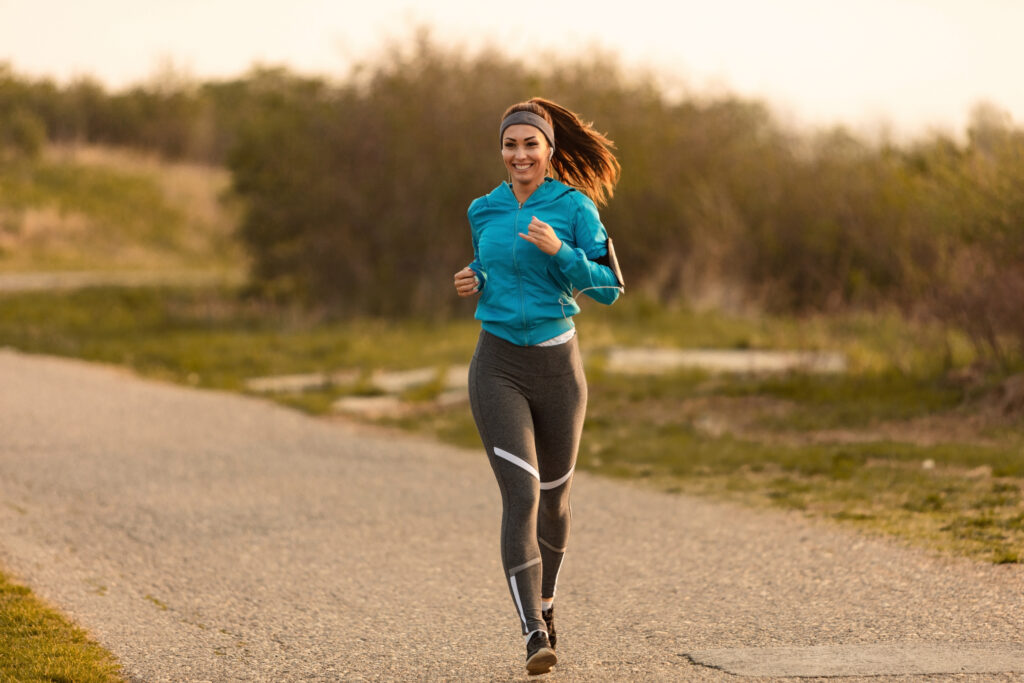 Young happy sportswoman running on the road in the morning working on building her self-belief.