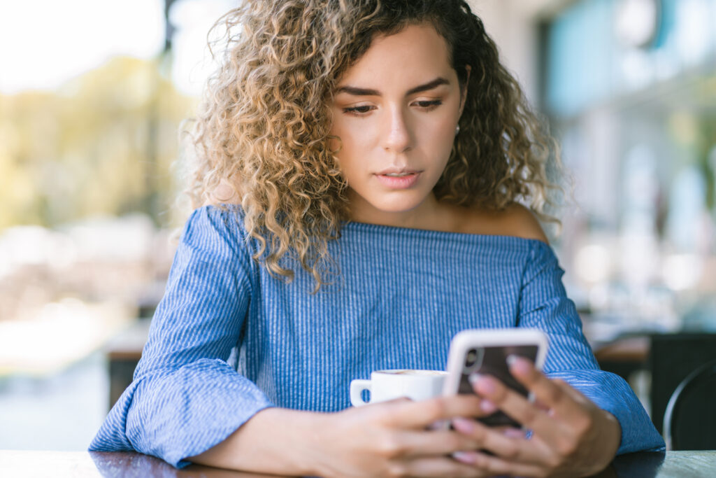 Woman looking at her phone trying to not let go of negative body control.