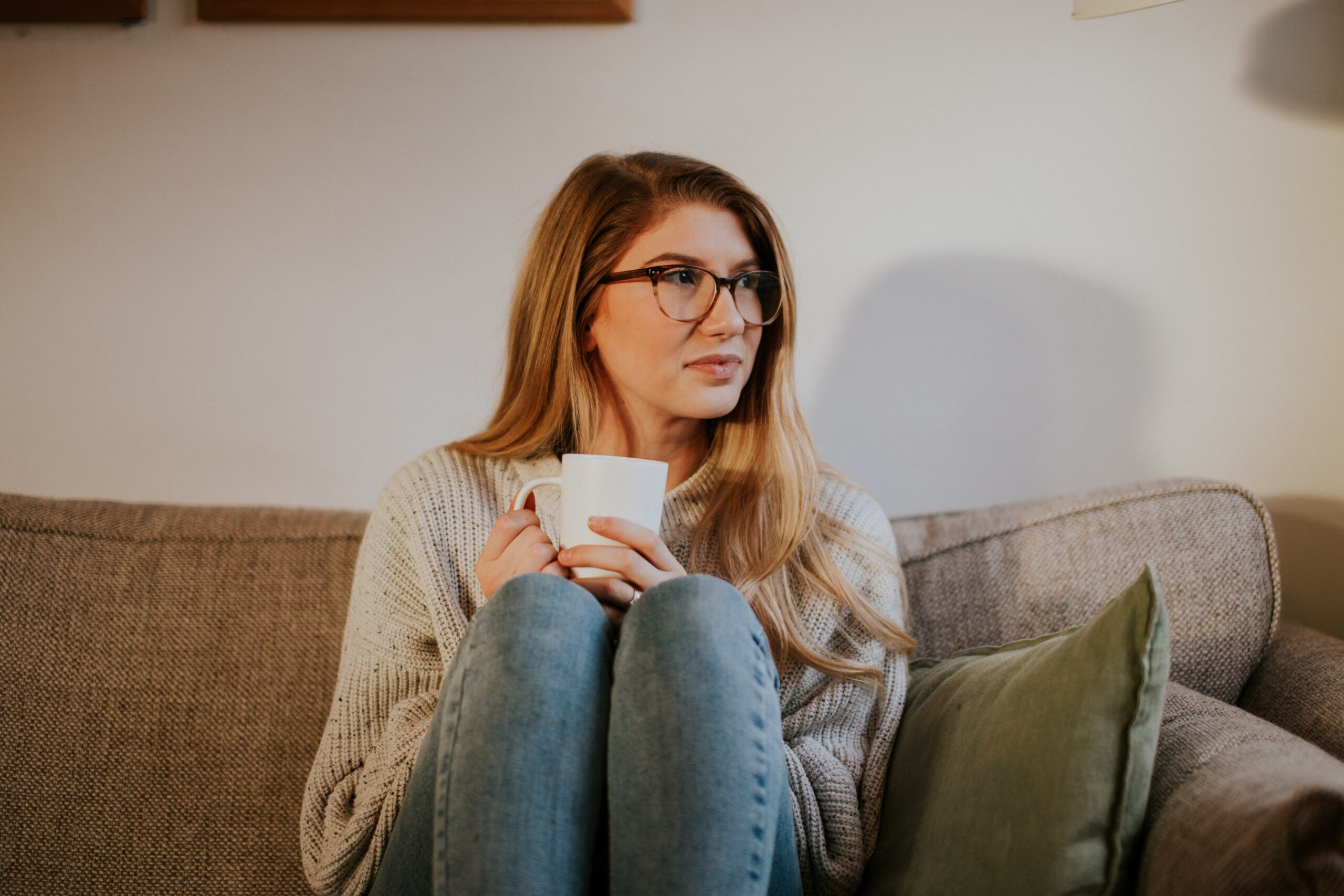 Girl drinking coffee on a cosy sofa. Listening to her emotions