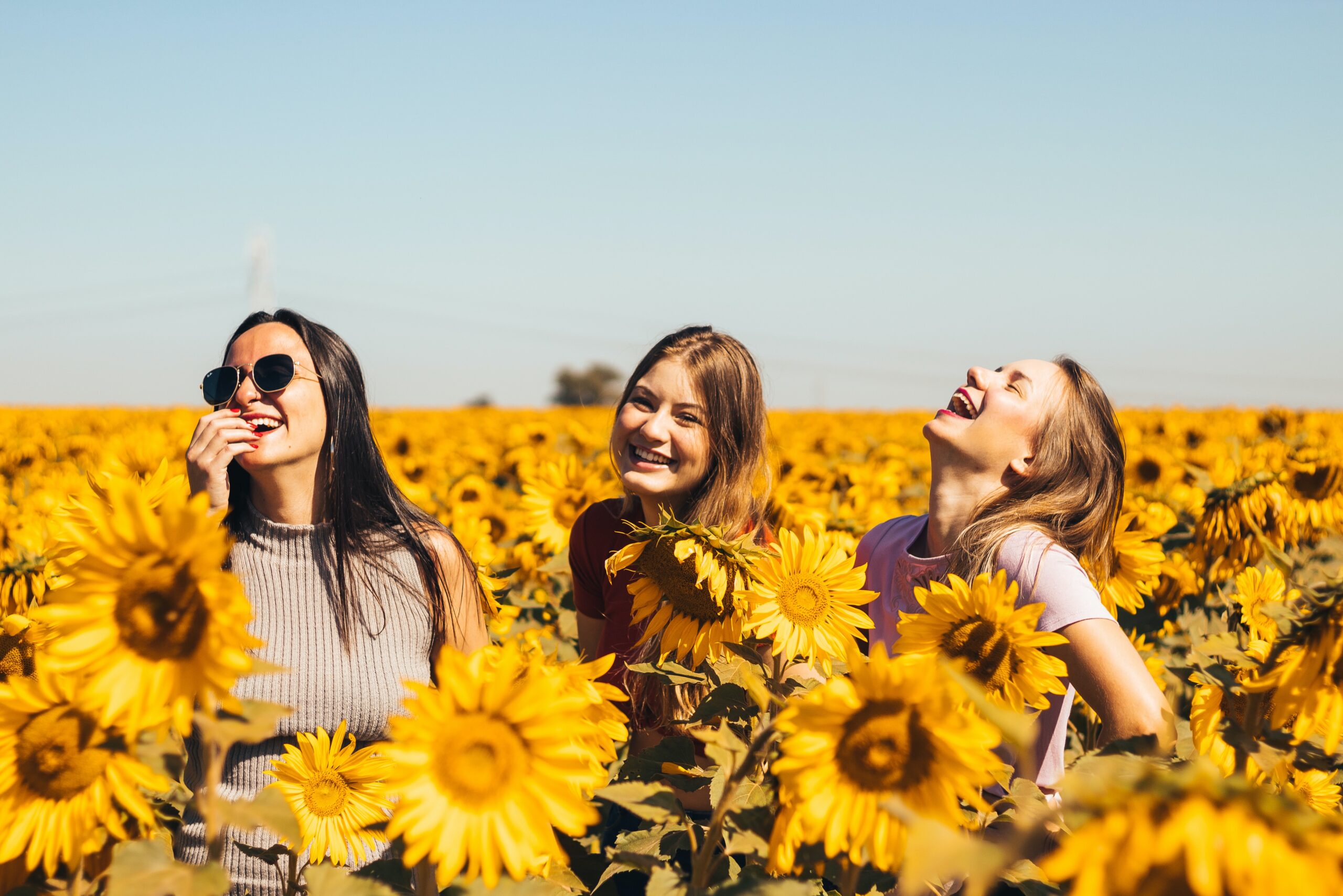3 women amongst sunflowers feeling confident and happy with positive self-esteem