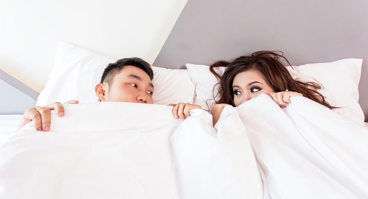 couple in bed hiding under covers lacking intimacy