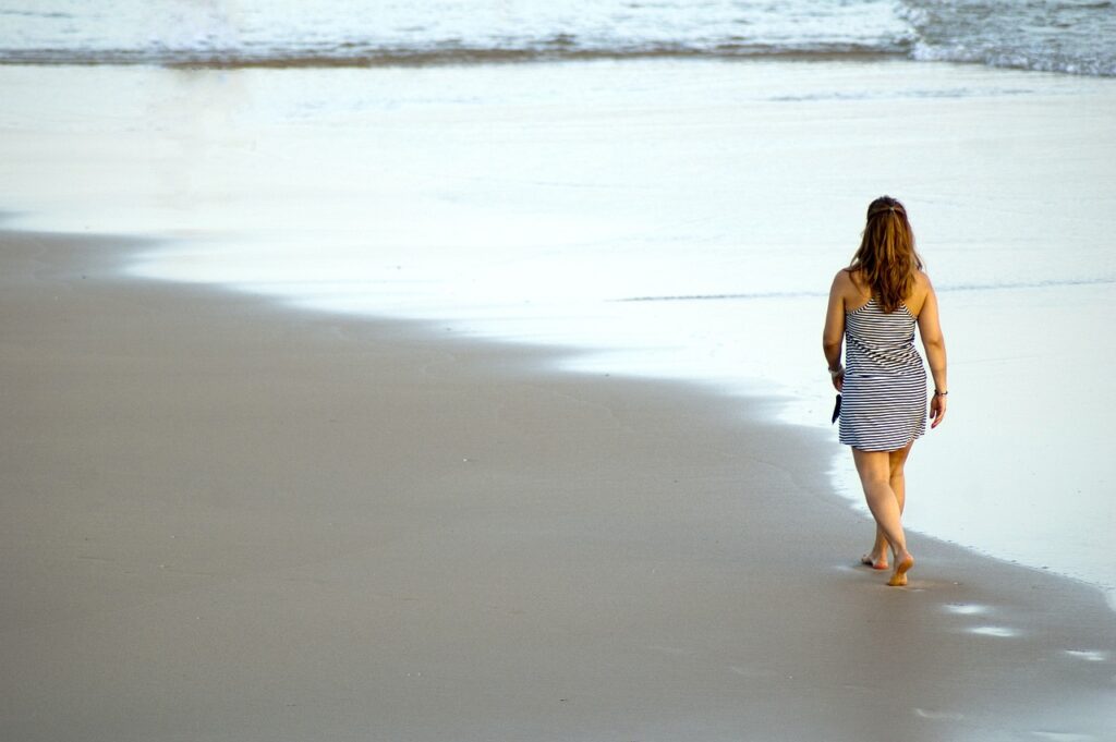 Woman taking a stroll along the beach having time to herself to practice self-love