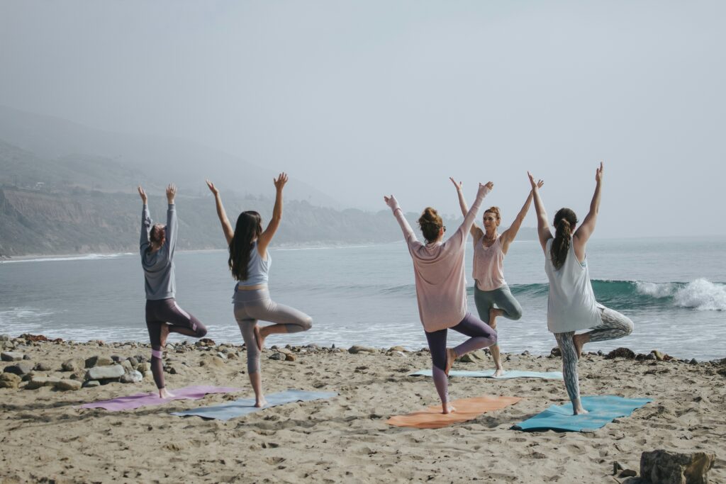 Group of women doing yoga on the beach practicing self-care as a form of self-love