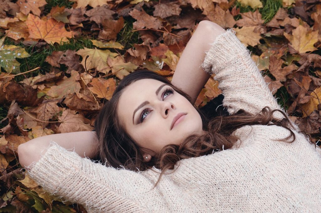 woman lying in autumn leaves thinking