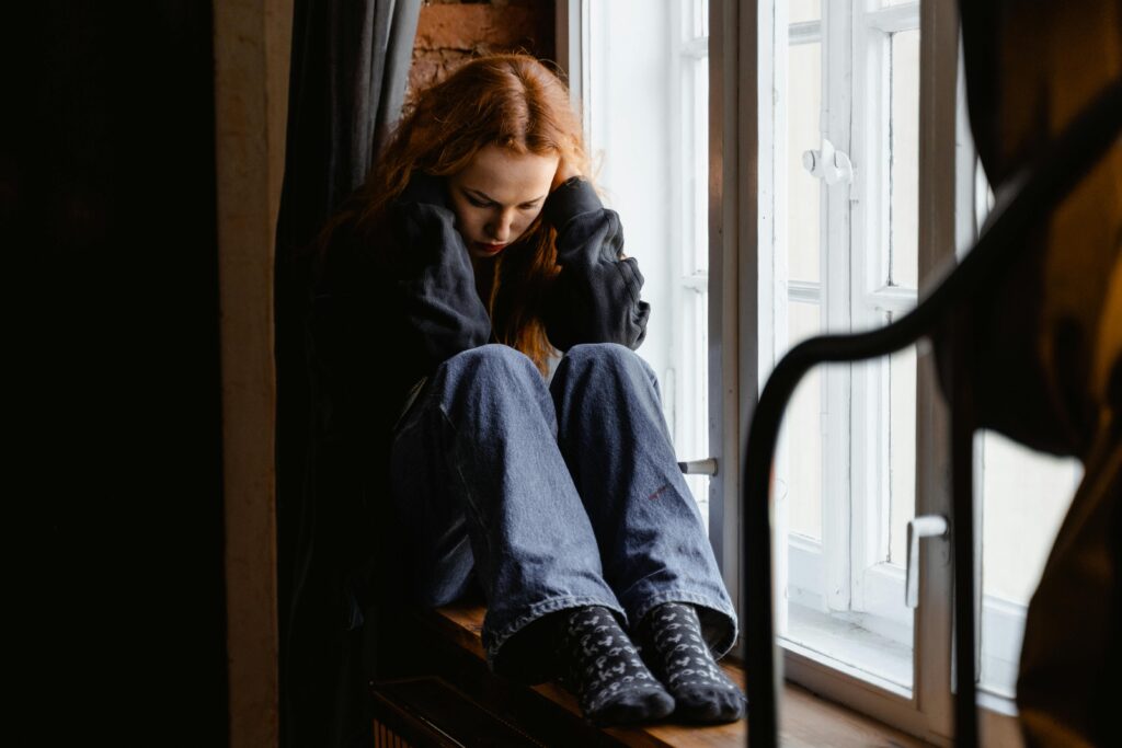 Woman sitting alone on a bench, reflecting on challenges and moments that impacted self-worth.