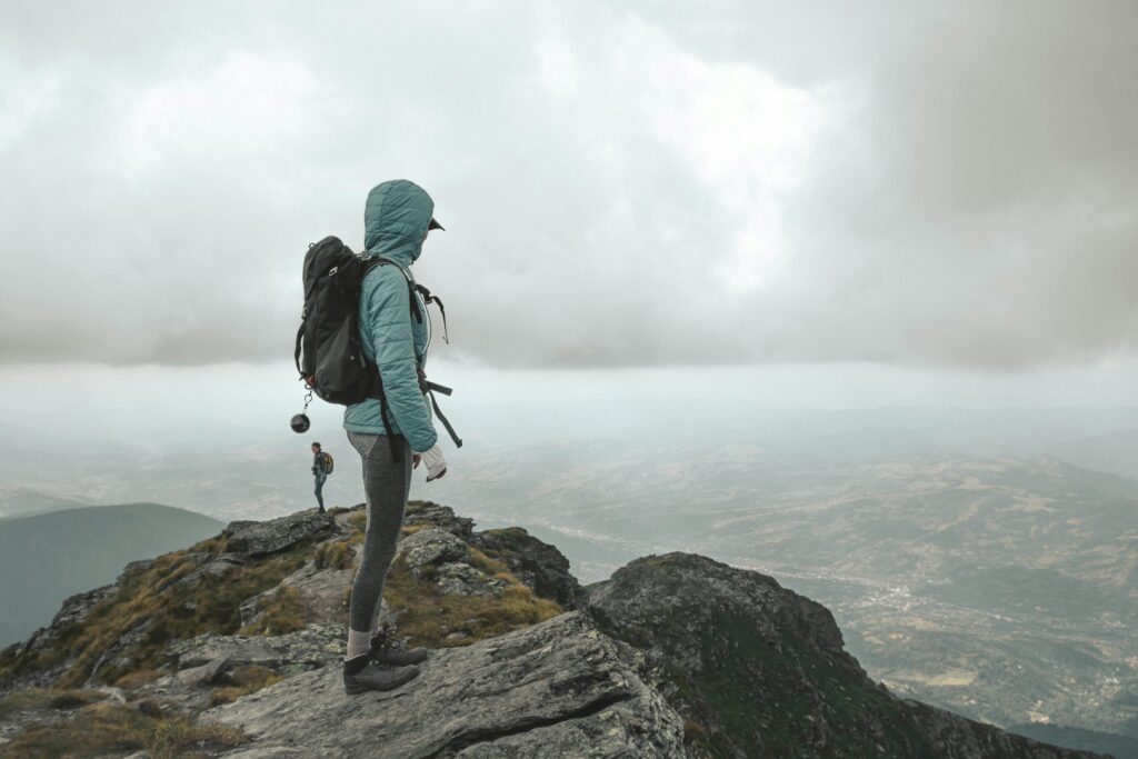 Person standing on a mountain peak, symbolising personal growth and building confidence.