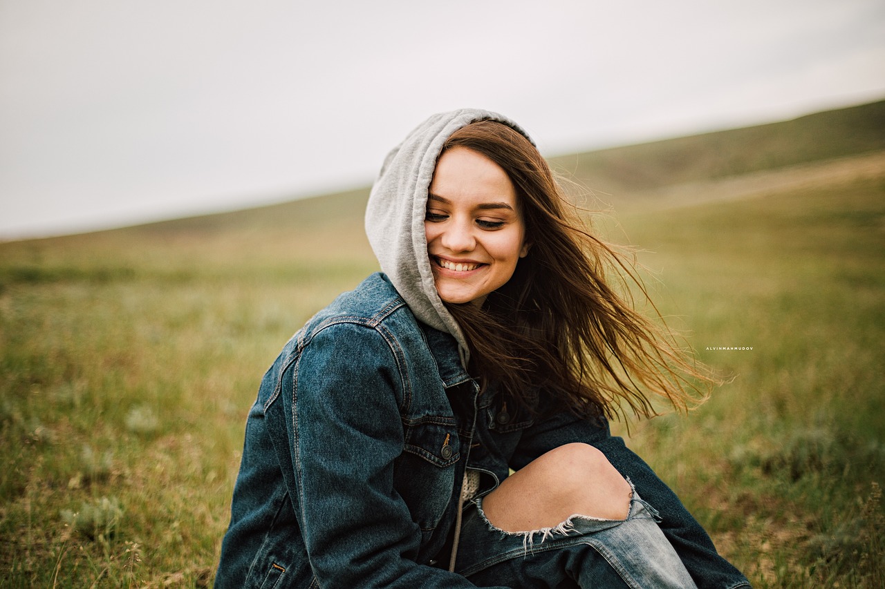 Confident woman smiling in nature, symbolising positivity and self-worth for 2025.